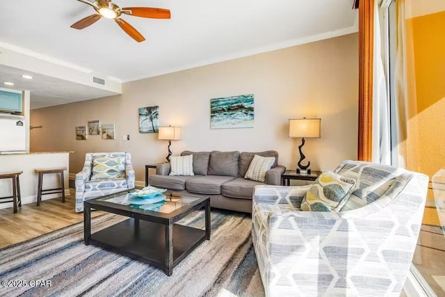 living room featuring ceiling fan, crown molding, and wood-type flooring