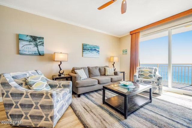 living room featuring ceiling fan, light wood-type flooring, a water view, and ornamental molding