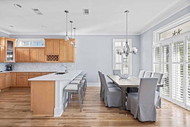 dining room featuring an inviting chandelier, ornamental molding, light hardwood / wood-style flooring, and sink