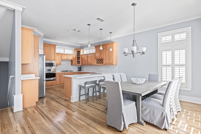 dining room with sink, an inviting chandelier, crown molding, and light hardwood / wood-style flooring