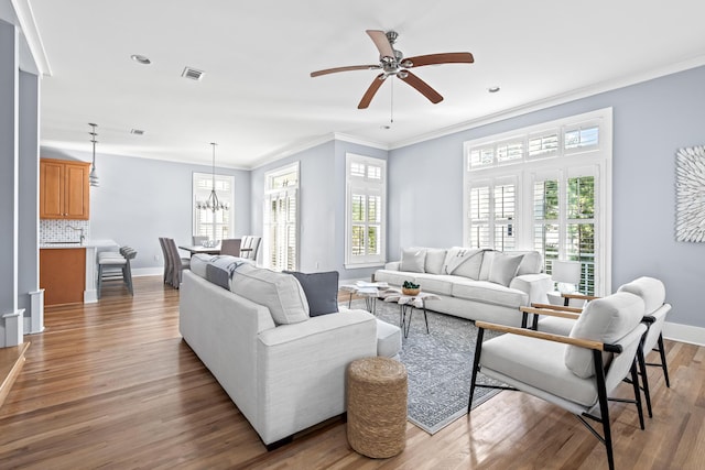 living room featuring ceiling fan with notable chandelier, ornamental molding, and hardwood / wood-style flooring