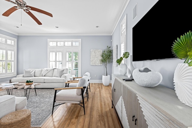 living room with ceiling fan, light wood-type flooring, crown molding, and plenty of natural light