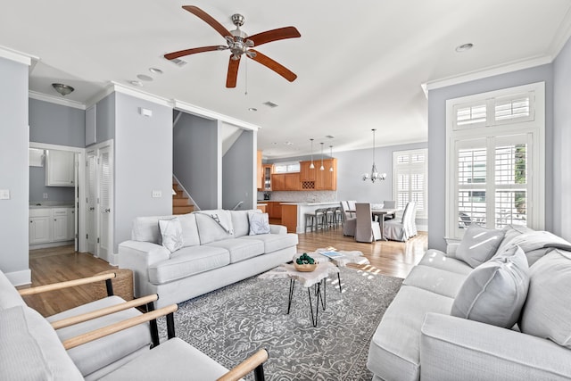 living room featuring ceiling fan, light hardwood / wood-style floors, and ornamental molding