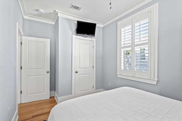 bedroom with a closet, crown molding, and hardwood / wood-style floors