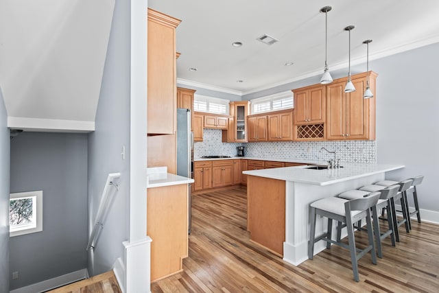 kitchen with kitchen peninsula, decorative light fixtures, a breakfast bar, tasteful backsplash, and sink