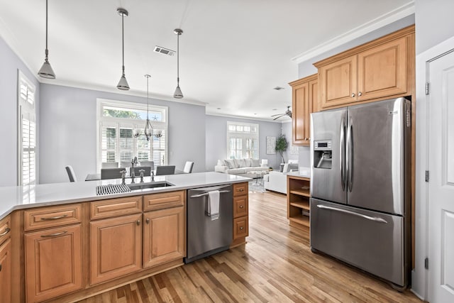 kitchen with sink, light wood-type flooring, ceiling fan with notable chandelier, hanging light fixtures, and appliances with stainless steel finishes