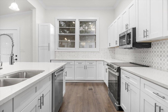 kitchen featuring appliances with stainless steel finishes, white cabinetry, sink, decorative light fixtures, and dark hardwood / wood-style flooring