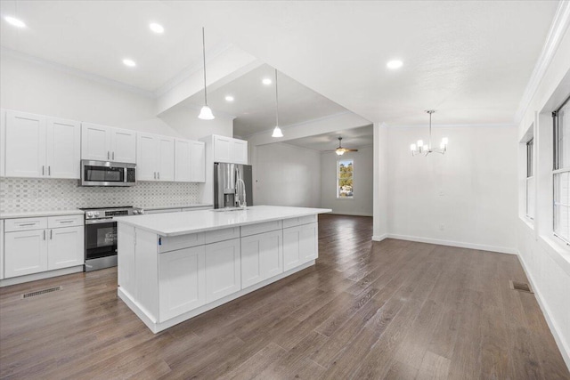 kitchen featuring decorative light fixtures, backsplash, white cabinetry, a center island with sink, and stainless steel appliances