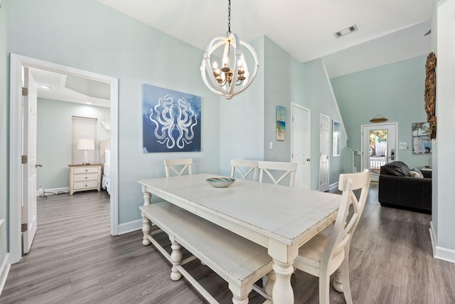 dining area featuring lofted ceiling, hardwood / wood-style floors, and an inviting chandelier