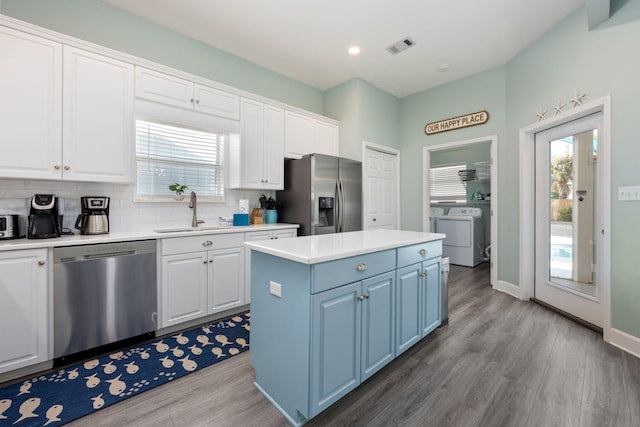 kitchen with stainless steel appliances, white cabinetry, a center island, and sink