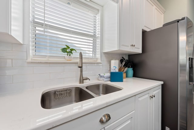 kitchen with white cabinetry, sink, decorative backsplash, and stainless steel refrigerator with ice dispenser