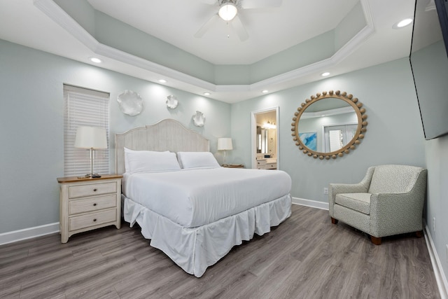 bedroom featuring hardwood / wood-style flooring, ceiling fan, a raised ceiling, and ensuite bath