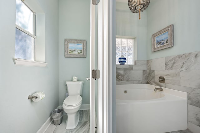 bathroom featuring a washtub, a wealth of natural light, and toilet