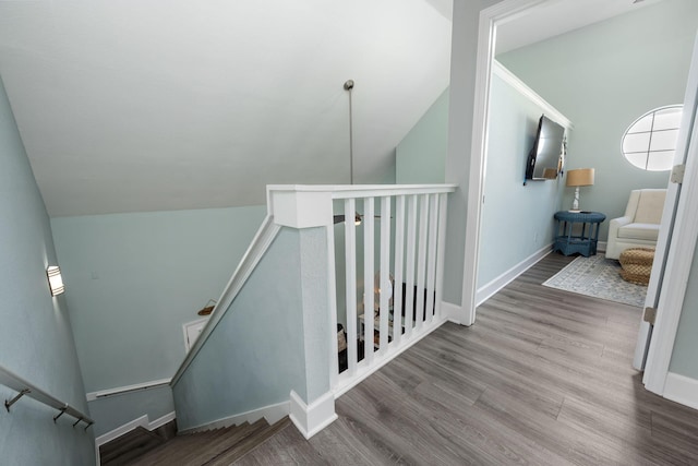 staircase featuring wood-type flooring and vaulted ceiling