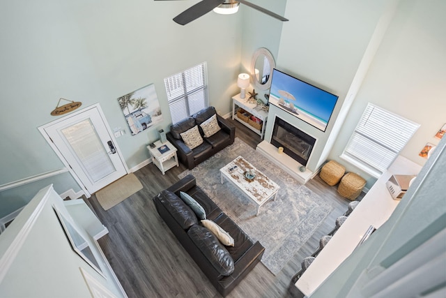 living room featuring a towering ceiling, dark wood-type flooring, and ceiling fan