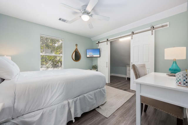 bedroom featuring hardwood / wood-style flooring, ceiling fan, and a barn door