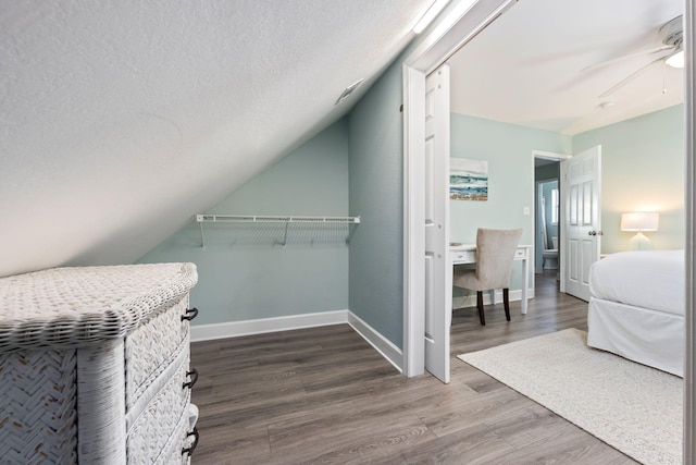 spacious closet featuring hardwood / wood-style flooring, vaulted ceiling, and ceiling fan