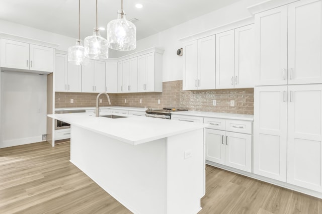 kitchen featuring a center island with sink, white cabinetry, pendant lighting, and sink