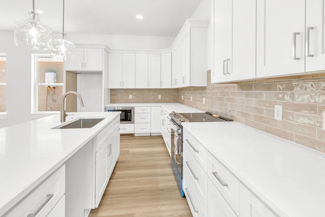 kitchen with stainless steel electric stove, sink, decorative light fixtures, white cabinetry, and black microwave