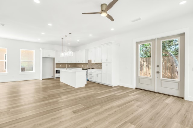 kitchen featuring light hardwood / wood-style flooring, pendant lighting, a center island with sink, white cabinetry, and ceiling fan