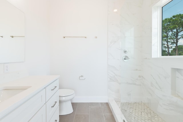 bathroom with toilet, tiled shower, a wealth of natural light, and vanity