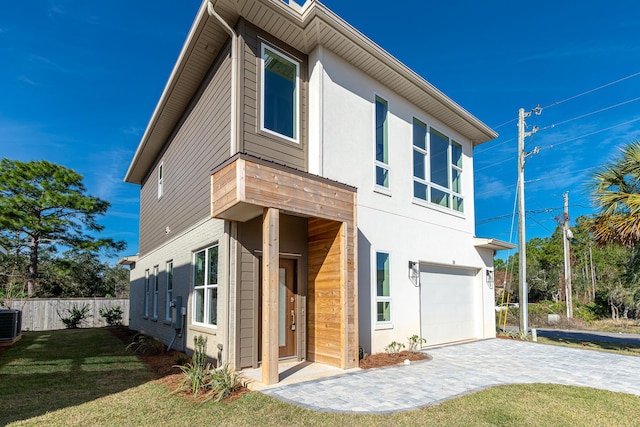 exterior space featuring central air condition unit, a front yard, and a garage