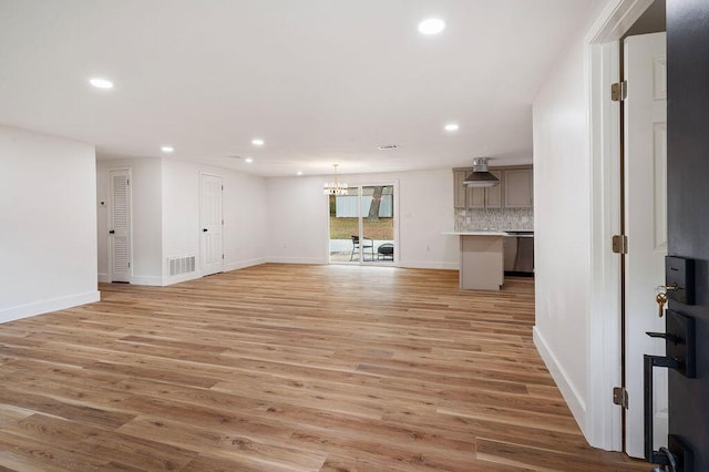 unfurnished living room with light hardwood / wood-style floors and a notable chandelier