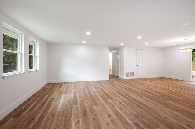 empty room featuring hardwood / wood-style floors, a notable chandelier, and plenty of natural light