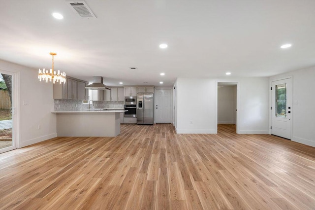 kitchen with backsplash, appliances with stainless steel finishes, gray cabinets, and light hardwood / wood-style flooring