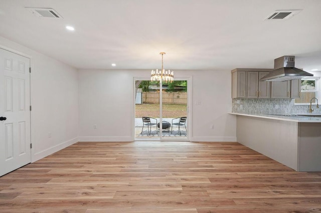 unfurnished dining area featuring an inviting chandelier, light hardwood / wood-style floors, and sink