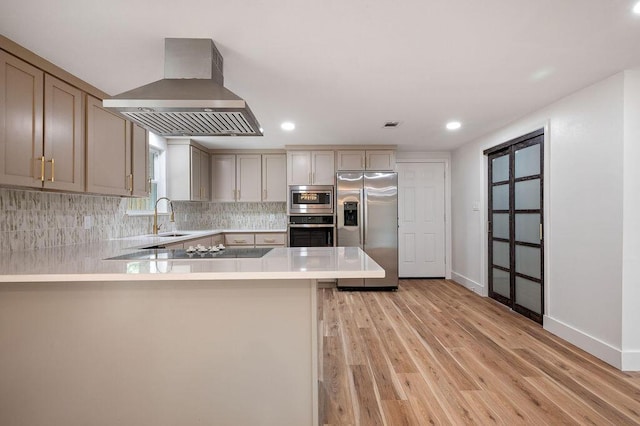 kitchen with kitchen peninsula, appliances with stainless steel finishes, island range hood, and sink