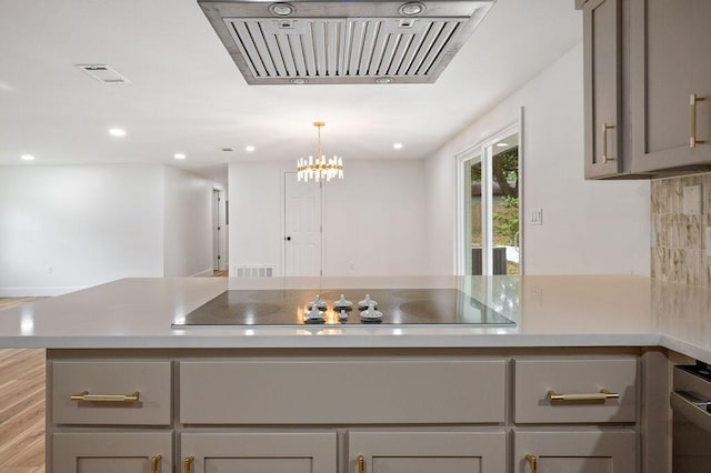 kitchen featuring exhaust hood, black electric stovetop, decorative light fixtures, and gray cabinets