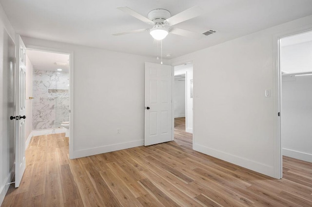 unfurnished bedroom featuring ceiling fan, light wood-type flooring, connected bathroom, a closet, and a walk in closet