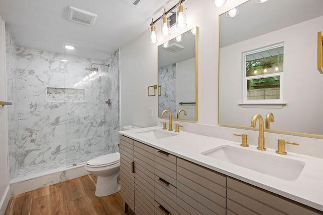 bathroom with a tile shower, vanity, toilet, and hardwood / wood-style flooring