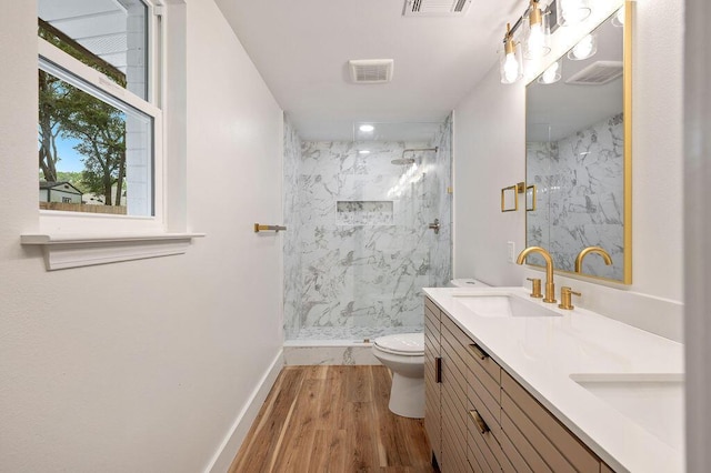 bathroom with toilet, vanity, tiled shower, and hardwood / wood-style floors