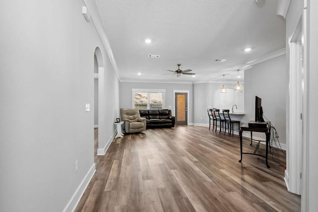 interior space with a textured ceiling, ornamental molding, and hardwood / wood-style flooring