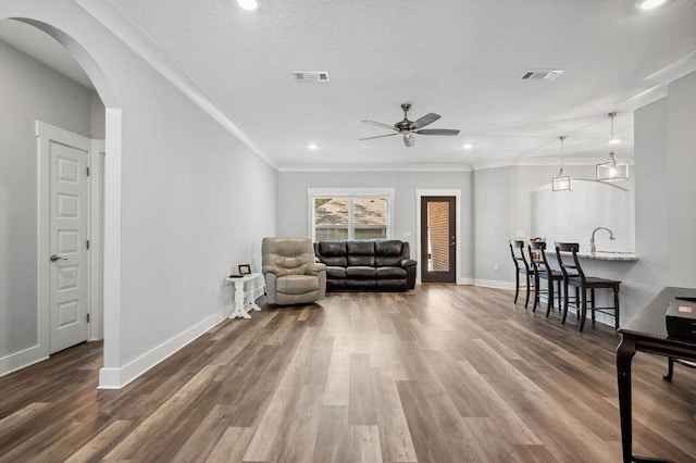 sitting room featuring wood-type flooring, a textured ceiling, ceiling fan, and crown molding