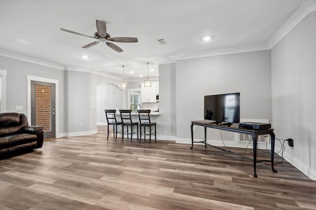 living room with ornamental molding, ceiling fan, and light hardwood / wood-style flooring