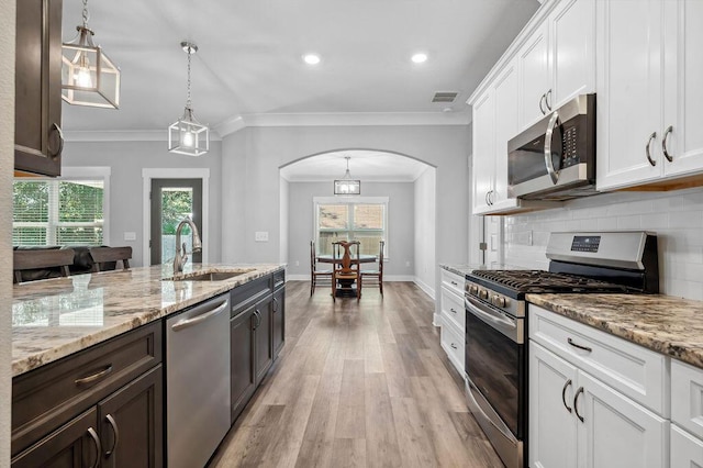 kitchen with hanging light fixtures, stainless steel appliances, tasteful backsplash, white cabinetry, and sink