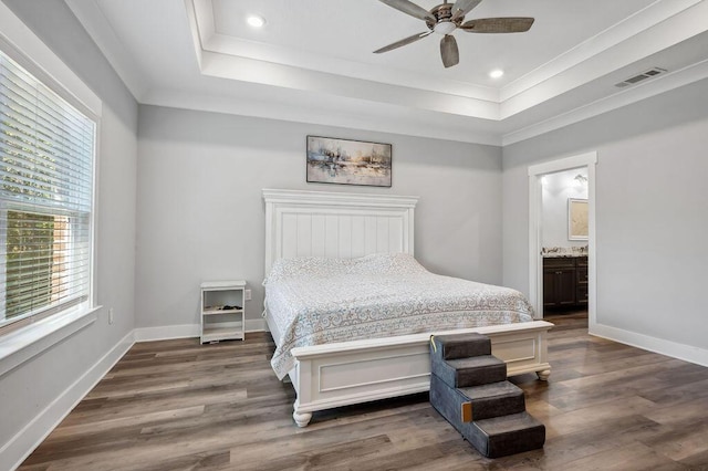 bedroom featuring connected bathroom, a raised ceiling, ceiling fan, and dark hardwood / wood-style flooring