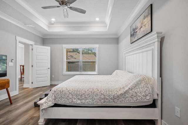 bedroom featuring wood-type flooring, a raised ceiling, ceiling fan, and ornamental molding