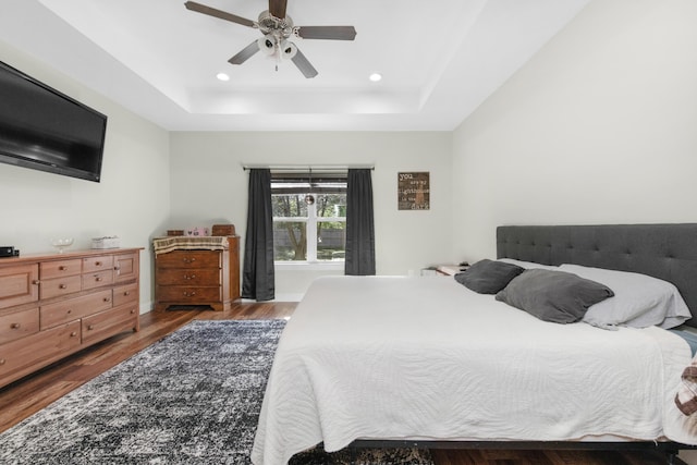 bedroom featuring ceiling fan, hardwood / wood-style flooring, and a tray ceiling