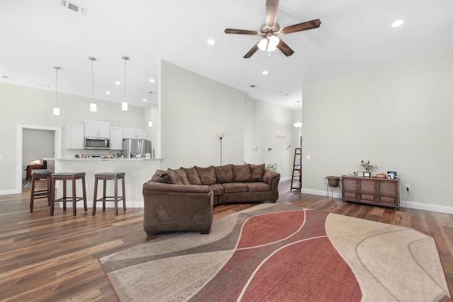 living room featuring a high ceiling, ceiling fan, and dark hardwood / wood-style flooring