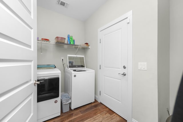 laundry room with washing machine and clothes dryer and dark hardwood / wood-style flooring