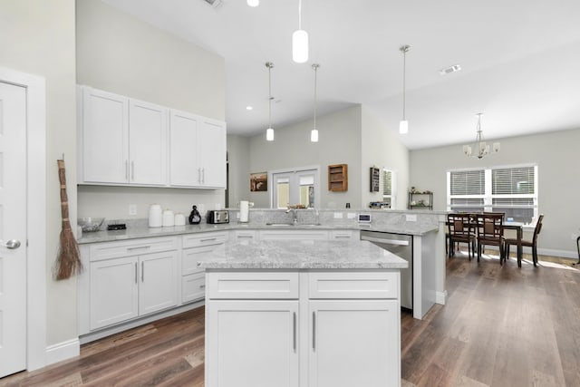 kitchen with hanging light fixtures, kitchen peninsula, sink, white cabinetry, and stainless steel dishwasher