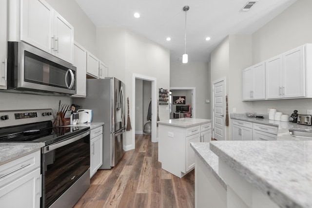 kitchen featuring stainless steel appliances, white cabinets, light stone counters, and hanging light fixtures