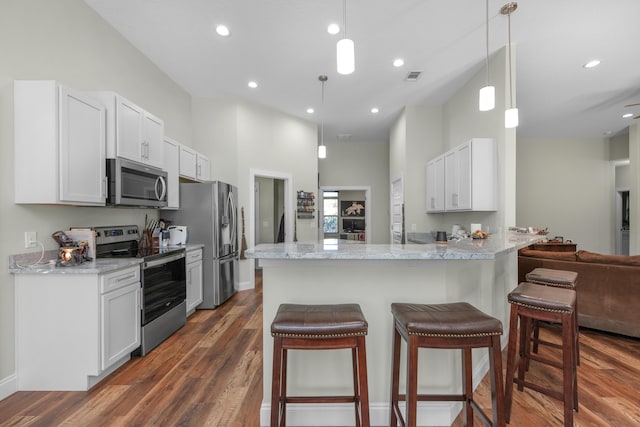 kitchen featuring white cabinets, stainless steel appliances, decorative light fixtures, and kitchen peninsula