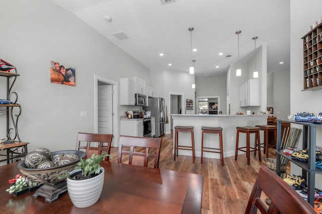 dining space featuring high vaulted ceiling and dark hardwood / wood-style flooring