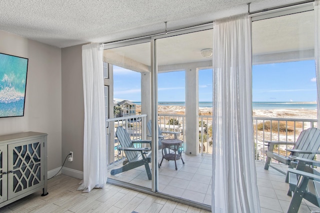 doorway to outside with a beach view, a wall of windows, and a water view