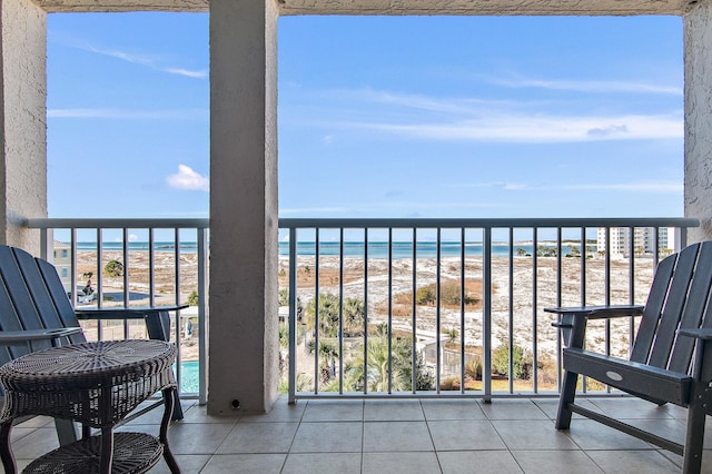 balcony with a water view and a view of the beach